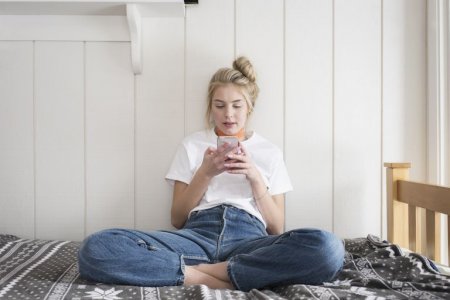 teen-girl-with-phone-sitting-on-bed-royalty-free-image-892457770-1548150292.jpg